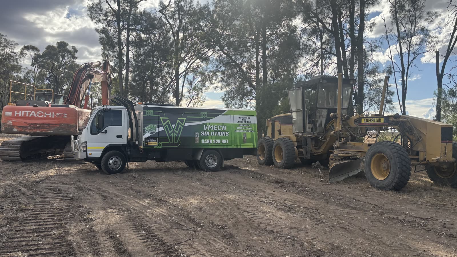 VMECH truck between a Hitachi excavator and a Cat grader on a cleared site